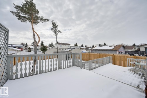 Expansive deck with grey railings and a privacy lattice, offering views of the surrounding neighborhood and mature trees - 8507 152B Avenue, Edmonton, AB - Outdoor