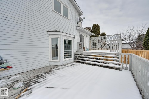 The property features an exterior with light-colored siding, a bay window, and a wooden deck with steps and a lattice privacy screen - 8507 152B Avenue, Edmonton, AB - Outdoor With Exterior