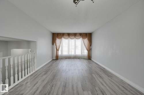 The spacious interior features light-toned flooring, light-colored walls, and a window with elegant drapes - 8507 152B Avenue, Edmonton, AB - Indoor Photo Showing Other Room