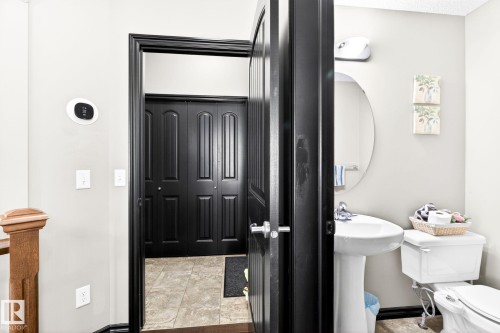 This property features a bathroom with a pedestal sink, a toilet, and an oval mirror - 1121 59A Street, Edmonton, AB - Indoor Photo Showing Bathroom
