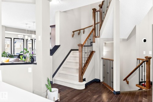 The property features dark hardwood flooring, a staircase with white carpeted treads, and a wooden handrail with black iron balusters - 1121 59A Street, Edmonton, AB - Indoor Photo Showing Other Room