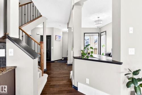 The property features rich hardwood flooring, a staircase with dark wrought iron spindles and a wooden handrail, and a decorative chandelier - 1121 59A Street, Edmonton, AB - Indoor Photo Showing Other Room