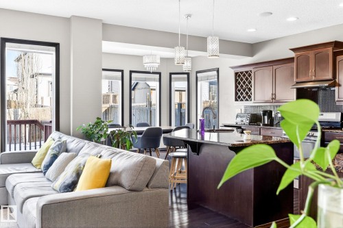 The property features an open-concept living area with large windows providing natural light, a kitchen with dark cabinetry and a built-in wine rack, and a dining area with modern pendant lighting - 1121 59A Street, Edmonton, AB - Indoor