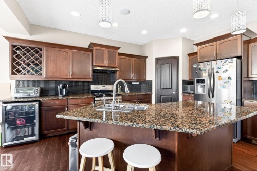 Kitchen featuring a large island with granite countertops, rich wood cabinetry, stainless steel appliances, and dark hardwood floors - 1121 59A Street, Edmonton, AB - Indoor Photo Showing Kitchen With Double Sink With Upgraded Kitchen