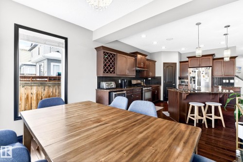 The open concept kitchen features rich wood cabinetry, stainless steel appliances, and a central island with bar seating - 1121 59A Street, Edmonton, AB - Indoor Photo Showing Dining Room
