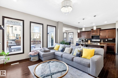The property features an open-concept living area with dark hardwood flooring and a contemporary chandelier - 1121 59A Street, Edmonton, AB - Indoor Photo Showing Living Room
