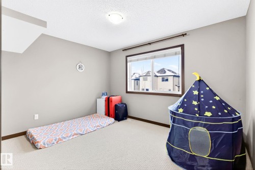This room features neutral-toned walls, a textured carpet, and a window with a brown frame - 1121 59A Street, Edmonton, AB - Indoor Photo Showing Bedroom