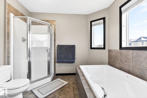 The bathroom features a glass-enclosed shower with a chrome fixture, a white toilet, and a white bathtub with a chrome faucet - 1121 59A Street, Edmonton, AB - Indoor Photo Showing Bathroom