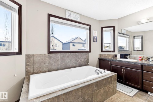 The bathroom features a built-in bathtub with a tiled surround, a vanity with dark wood cabinetry, and a large mirror - 1121 59A Street, Edmonton, AB - Indoor Photo Showing Bathroom