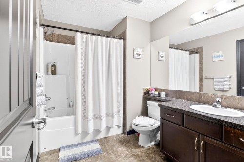 Bathroom featuring a vanity with a dark countertop, an undermount sink, and dark wood cabinetry - 1121 59A Street, Edmonton, AB - Indoor Photo Showing Bathroom
