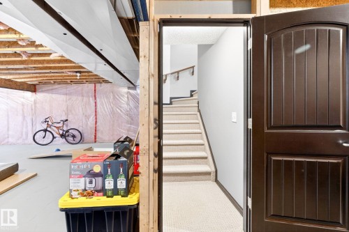 The property features a finished staircase with carpeted treads and a wooden handrail, leading from a dark wood paneled door - 1121 59A Street, Edmonton, AB - Indoor Photo Showing Other Room