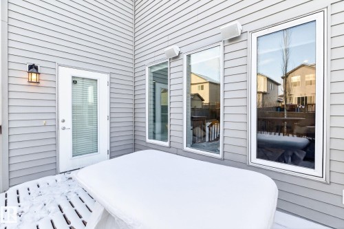The property features light gray horizontal siding, an outdoor wall lantern, and glass panel doors and windows - 1121 59A Street, Edmonton, AB - Outdoor With Deck Patio Veranda With Exterior