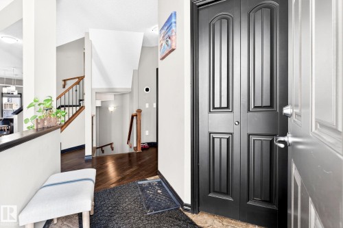 The entry features dark wood flooring, a staircase with wood handrails and black metal spindles, and a black double closet door - 1121 59A Street, Edmonton, AB - Indoor Photo Showing Other Room
