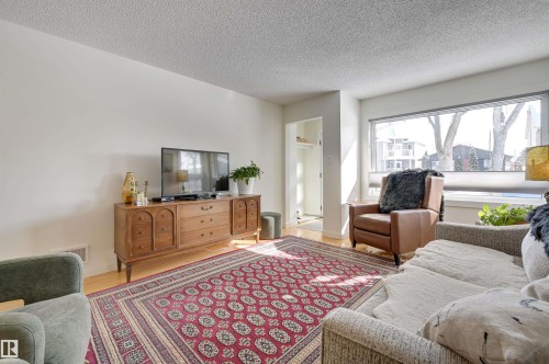 The living area features hardwood floors and a large window providing natural light - 11116 52 Street Nw, Edmonton, AB - Indoor