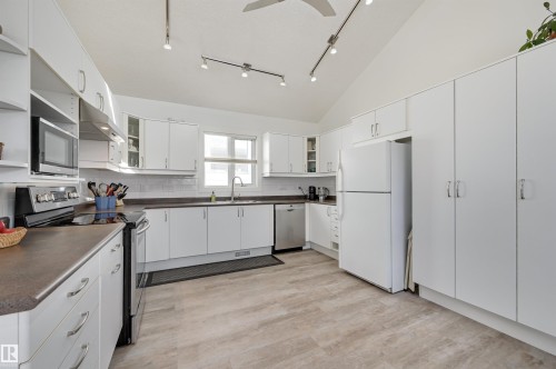 The kitchen features white cabinetry, a white refrigerator, a stainless steel dishwasher, and a microwave - 11116 52 Street Nw, Edmonton, AB - Indoor Photo Showing Kitchen