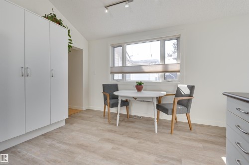 The dining area features light wood-look flooring, a window with blinds, and white walls - 11116 52 Street Nw, Edmonton, AB - Indoor Photo Showing Dining Room