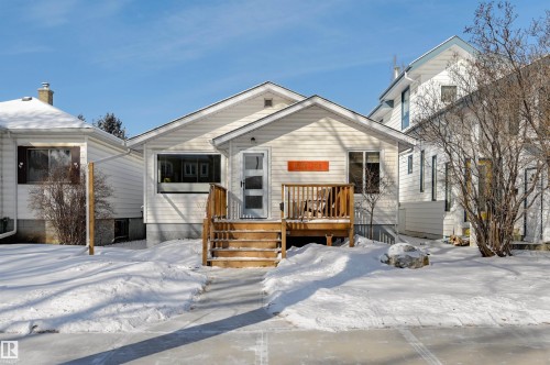The property features a white exterior, a front deck with wooden railing and stairs, and a visible front door - 11116 52 Street Nw, Edmonton, AB - Outdoor