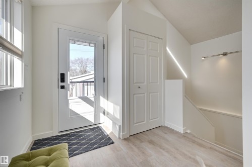 The property features an entryway with light-colored flooring, a white front door with a window, and an integrated closet with bi-fold doors - 11116 52 Street Nw, Edmonton, AB - Indoor Photo Showing Other Room