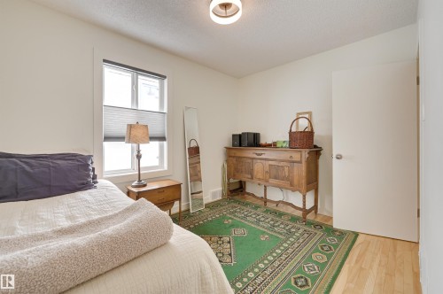 This room features light hardwood flooring, a window with blinds, and a ceiling light fixture - 11116 52 Street Nw, Edmonton, AB - Indoor Photo Showing Bedroom