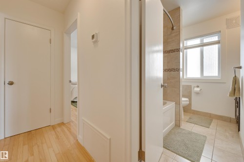 This bathroom features a bathtub with tiled surround, a window providing natural light, and tiled flooring - 11116 52 Street Nw, Edmonton, AB - Indoor