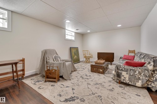 This spacious area features dark wood flooring, light-colored walls, and a dropped ceiling with recessed lighting - 11116 52 Street Nw, Edmonton, AB - Indoor Photo Showing Basement
