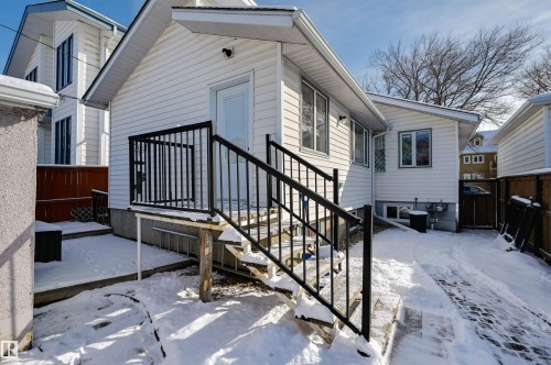 The property features white vinyl siding, exterior stairs with black railings, and a wooden fence - 11116 52 Street Nw, Edmonton, AB - Outdoor