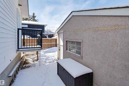 The property features a private balcony with black railings, a stucco exterior building, and a wooden fence - 11116 52 Street Nw, Edmonton, AB - Outdoor With Exterior