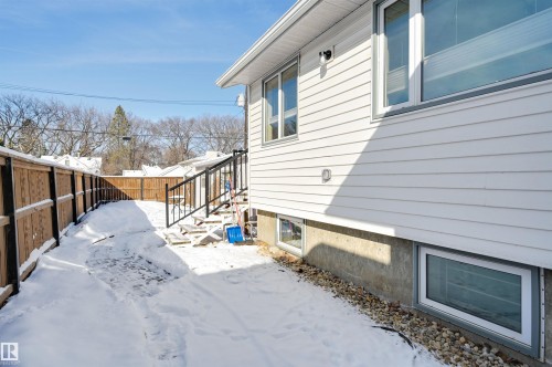 The property features white horizontal siding, a concrete foundation, and a wooden fence along the property line - 11116 52 Street Nw, Edmonton, AB - Outdoor With Exterior