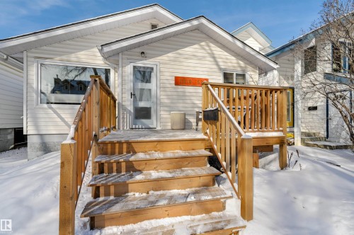 The property features a white exterior, a wood deck with stairs, and a front entrance with a screen door - 11116 52 Street Nw, Edmonton, AB - Outdoor With Exterior