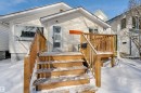 The property features a white exterior, a wood deck with stairs, and a front entrance with a screen door - 11116 52 Street Nw, Edmonton, AB  - Outdoor With Exterior 