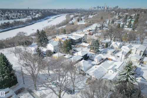 Aerial view of a residential area featuring numerous homes with snow-covered rooftops, surrounded by bare trees and evergreens - 11116 52 Street Nw, Edmonton, AB - Outdoor With View