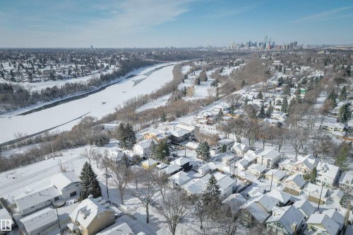 This property is located in a community featuring many homes with snow-covered roofs, mature trees, and a distant cityscape visible on the horizon - 11116 52 Street Nw, Edmonton, AB - Outdoor With View