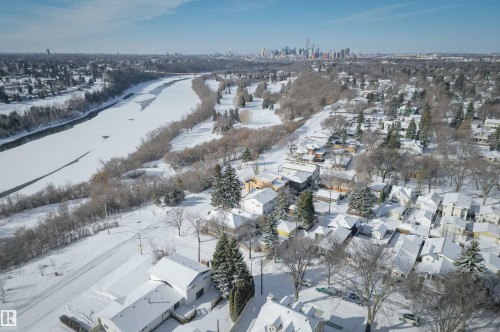 Aerial view of the neighborhood featuring properties with snow-covered roofs, surrounding trees, and a distant cityscape - 11116 52 Street Nw, Edmonton, AB - Outdoor With View