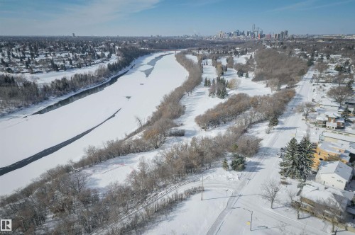 Aerial view showcasing a snow-covered landscape with a partially frozen river, surrounding trees, and nearby residential properties - 11116 52 Street Nw, Edmonton, AB - Outdoor With View