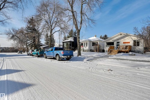 The property features a white exterior, a wood deck, and a wood staircase leading to the entrance - 11116 52 Street Nw, Edmonton, AB - Outdoor