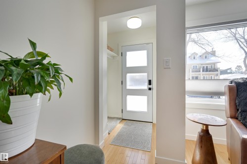 Entryway featuring light wood flooring, a modern white door with frosted glass panels, and a ceiling light fixture - 11116 52 Street Nw, Edmonton, AB - Indoor Photo Showing Other Room