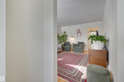 The living area features light-toned walls, wood flooring, and a decorative area rug - 11116 52 Street Nw, Edmonton, AB - Indoor Photo Showing Other Room