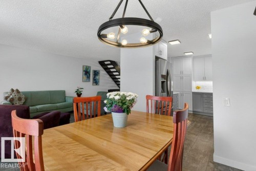 The dining area is illuminated by a modern circular chandelier - 91 Hearthstone, Edmonton, AB - Indoor Photo Showing Dining Room