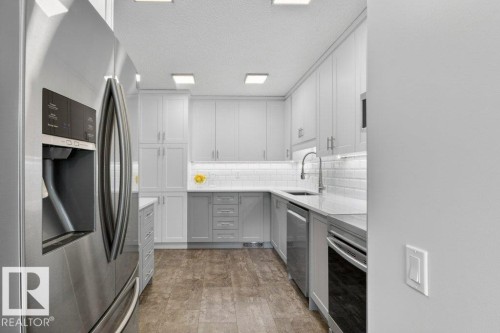 The kitchen features white & light grey cabinets, a white subway tile backsplash, quartz counters and stainless steel appliances - 91 Hearthstone, Edmonton, AB - Indoor Photo Showing Kitchen With Stainless Steel Kitchen With Upgraded Kitchen