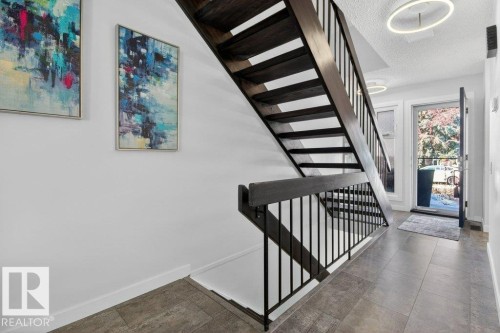 The property features a contemporary staircase with dark wood treads and sleek black metal railings - 91 Hearthstone, Edmonton, AB - Indoor Photo Showing Other Room