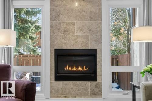 Living room featuring a gas fireplace with tile surround, and windows providing views of the outdoors - 91 Hearthstone, Edmonton, AB - Indoor Photo Showing Living Room With Fireplace