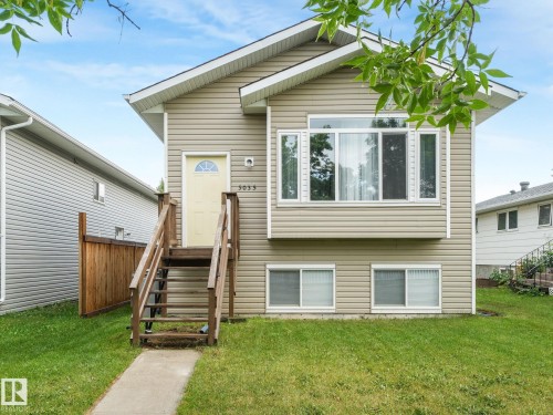 The property features a light-colored exterior siding and a front yard with a concrete pathway leading to a wooden staircase - 5035 51 Avenue, Lamont, AB - Outdoor