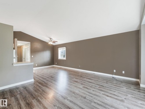 The property features a spacious room with wood-style flooring, a vaulted ceiling, and a ceiling fan - 5035 51 Avenue, Lamont, AB - Indoor Photo Showing Other Room