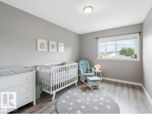 Bedroom with light grey walls, grey wood-style flooring, and a window providing natural light - 5035 51 Avenue, Lamont, AB - Indoor Photo Showing Bedroom