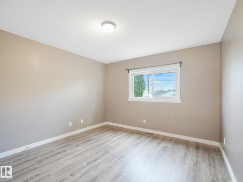 The room features neutral-toned walls, wood-look flooring, and a window with a view of the surrounding area - 5035 51 Avenue, Lamont, AB - Indoor Photo Showing Other Room