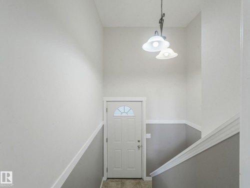 Entryway featuring a white door with a decorative window, a two-tone painted wall, and an overhead light fixture - 5035 51 Avenue, Lamont, AB - Indoor Photo Showing Other Room
