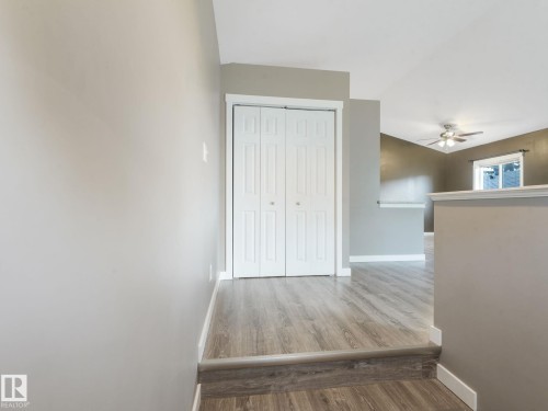 Interior view featuring light wood-look flooring, a closet with white bi-fold doors, and a ceiling fan in the background - 5035 51 Avenue, Lamont, AB - Indoor Photo Showing Other Room