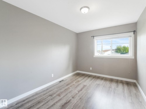 This room offers wood-look flooring, light grey painted walls, and a window providing natural light - 5035 51 Avenue, Lamont, AB - Indoor Photo Showing Other Room