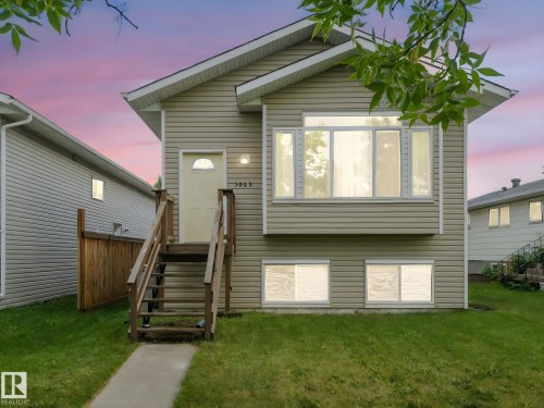The property features a light-colored exterior with a front entry staircase and a front yard with a lawn and sidewalk - 5035 51 Avenue, Lamont, AB - Outdoor