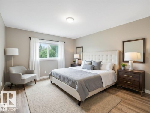 The property features a bedroom with light-colored walls and wood-style flooring - 5035 51 Avenue, Lamont, AB - Indoor Photo Showing Bedroom